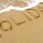 beach with holiday written in the sand