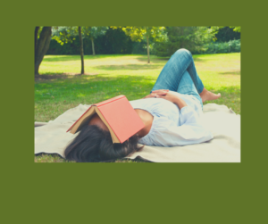 woman relaxing outdoors on blanket with a book over her face